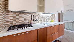 A kitchen with a gas stove, wooden cabinets, a white countertop, and a tiled backsplash.