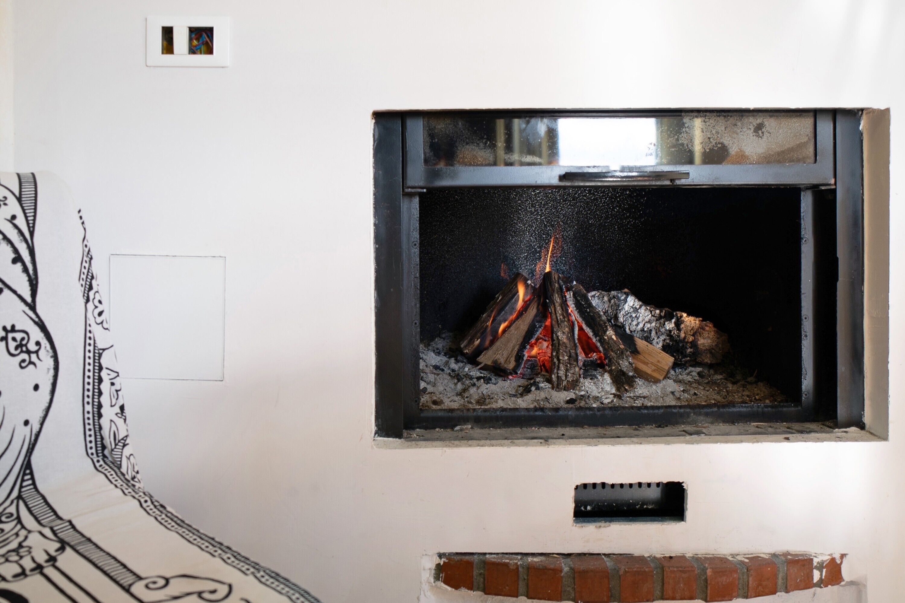 A fireplace with a fire, a window, and a wall with a decorative border.
