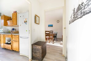 A kitchen with wooden cabinets, a white refrigerator, and a dining area with a table and chairs.