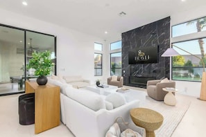 A modern living room with a sofa, coffee table, and a TV mounted on a black marble wall. - Anderson LUX Estate/Private Bar&Pool/Sleeps 12 (Scottsdale)