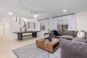 Un salon moderne avec un canapé, une table basse et un escalier.