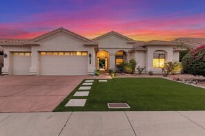 A two-story house with a front entrance, garage doors, and a well-maintained lawn.