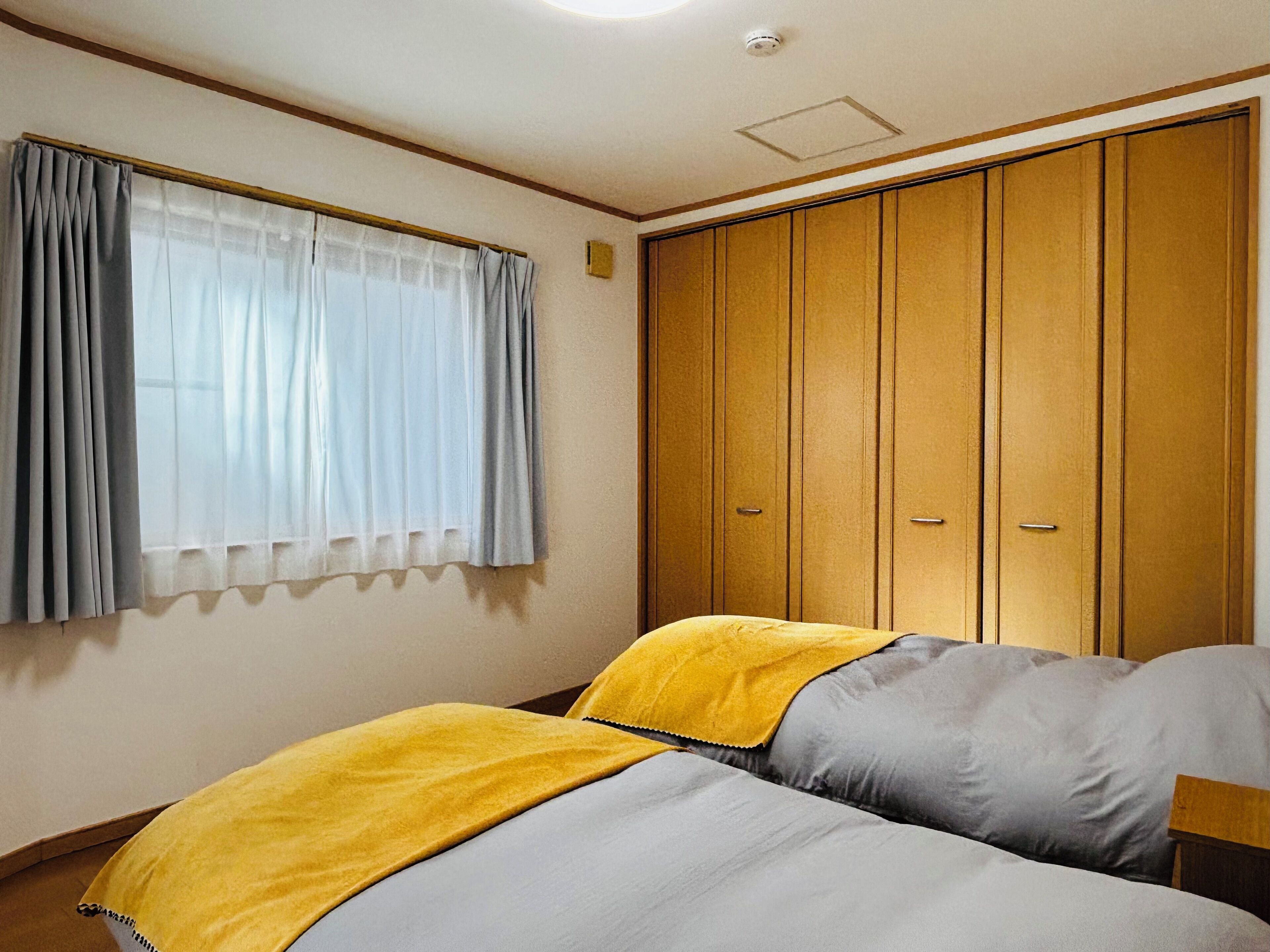 Une chambre à coucher avec un lit, une armoire et une fenêtre avec des rideaux.