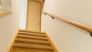 Una escalera de madera con barandilla y peldaños alfombrados que conducen a una puerta en la parte superior.