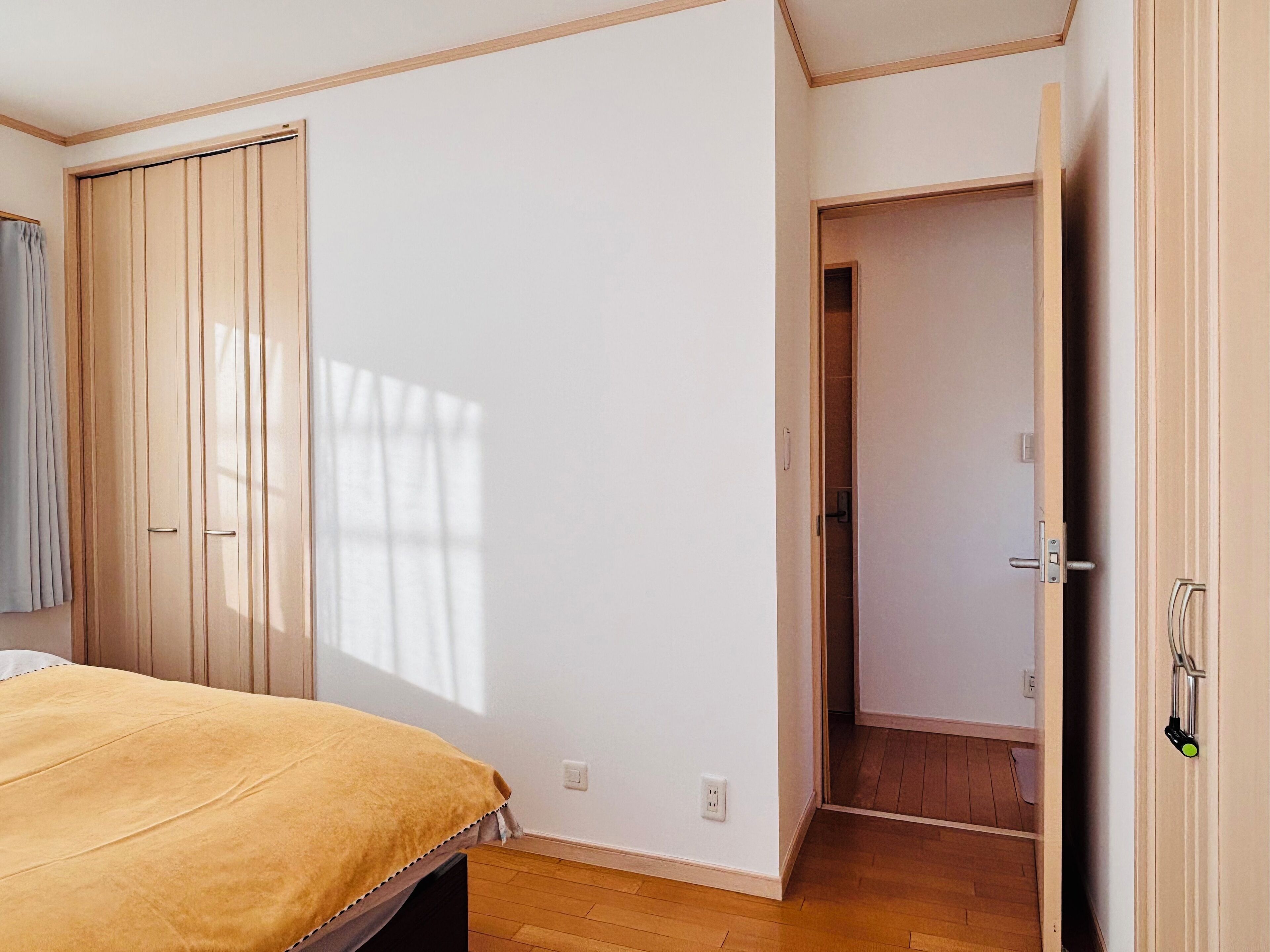 A bedroom with a bed, a wardrobe, and a door leading to another room.