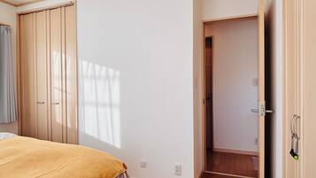 A bedroom with a bed, a wardrobe, and a door leading to another room.