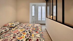 Un dormitorio con cama, una silla, una ventana y una puerta.