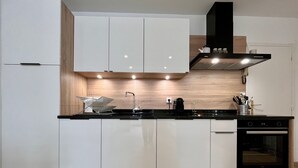 Una cocina moderna con armarios blancos, estufa negra y protector contra salpicaduras de madera.