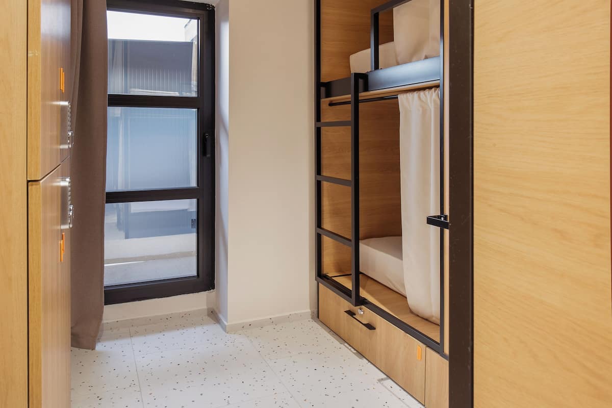 A compact room with a bunk bed, a wardrobe, and a door leading to an outdoor area.