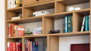 Una habitación con una estantería de madera llena de libros y un disco de vinilo. Un sillón tapizado rojo destaca en primer plano.
