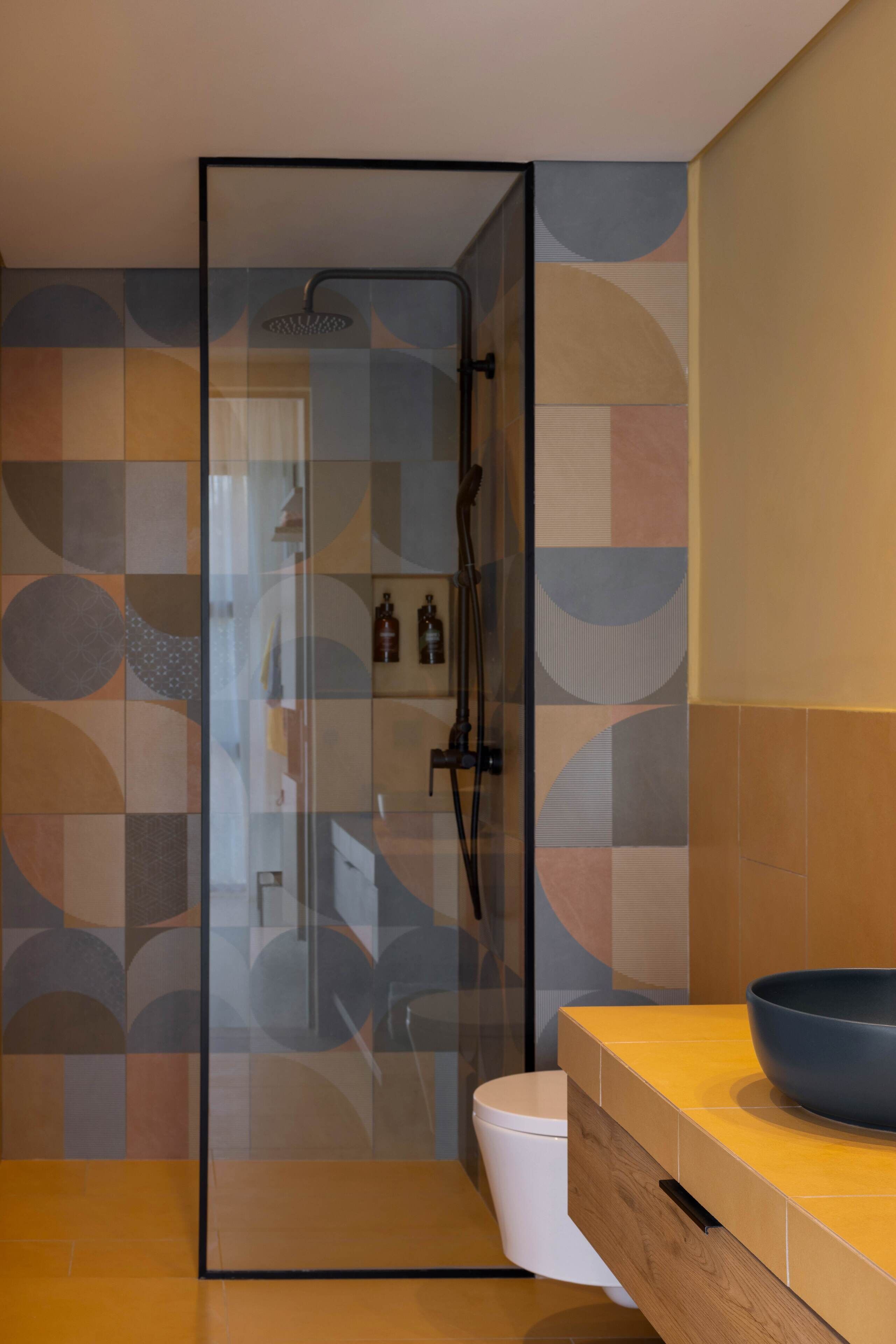 Une salle de bain moderne avec une douche à parois de verre, des toilettes blanches et un meuble-lavabo en bois doté d’un grand lavabo en forme de coupe.