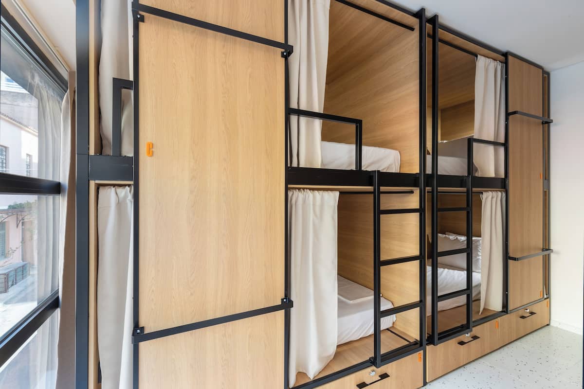 A room with a bunk bed, wooden walls, and a window.