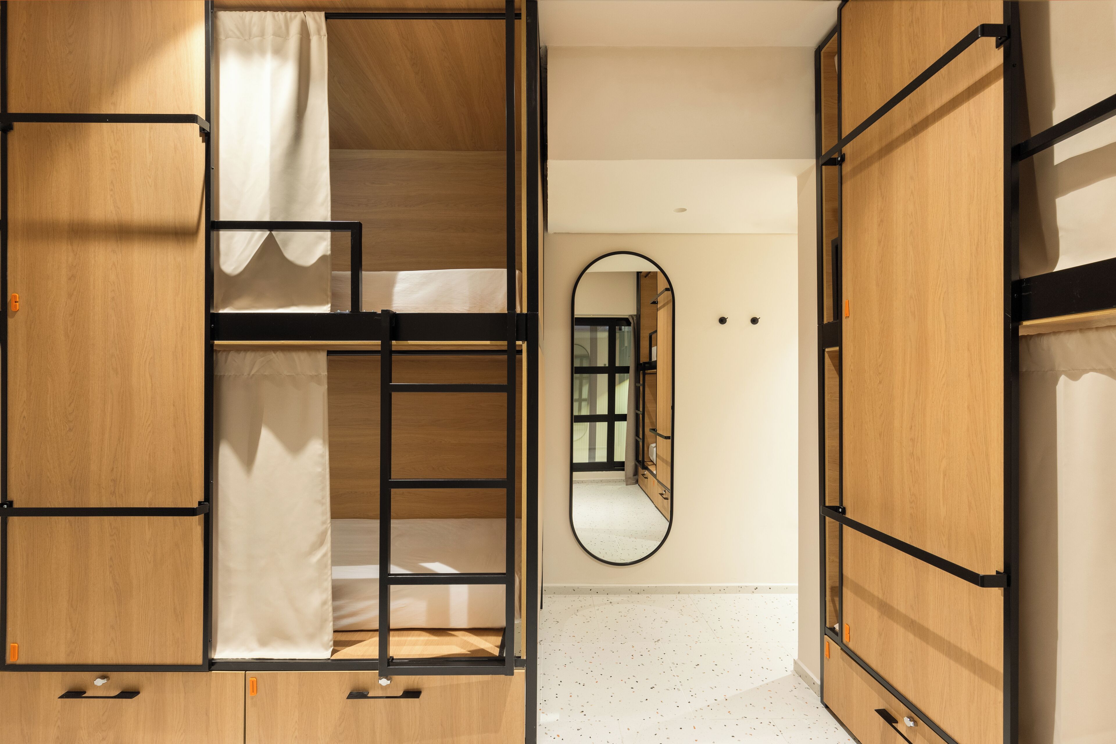 A room with a bunk bed, a mirror, and wooden furniture.
