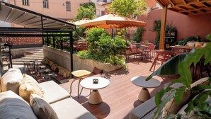 An outdoor patio with seating, a covered area, and a table with an umbrella. - Okupa (Athens)