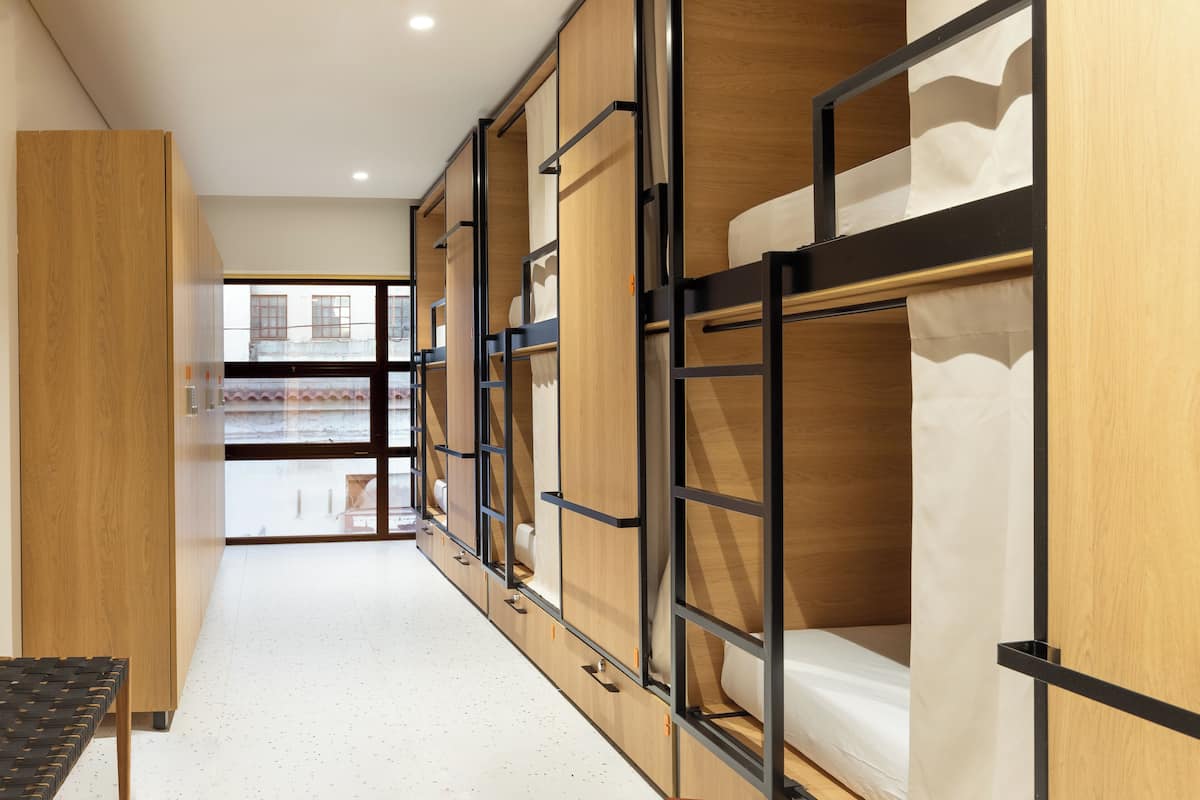 A modern hotel room with bunk beds, wooden walls, and a view of the city.