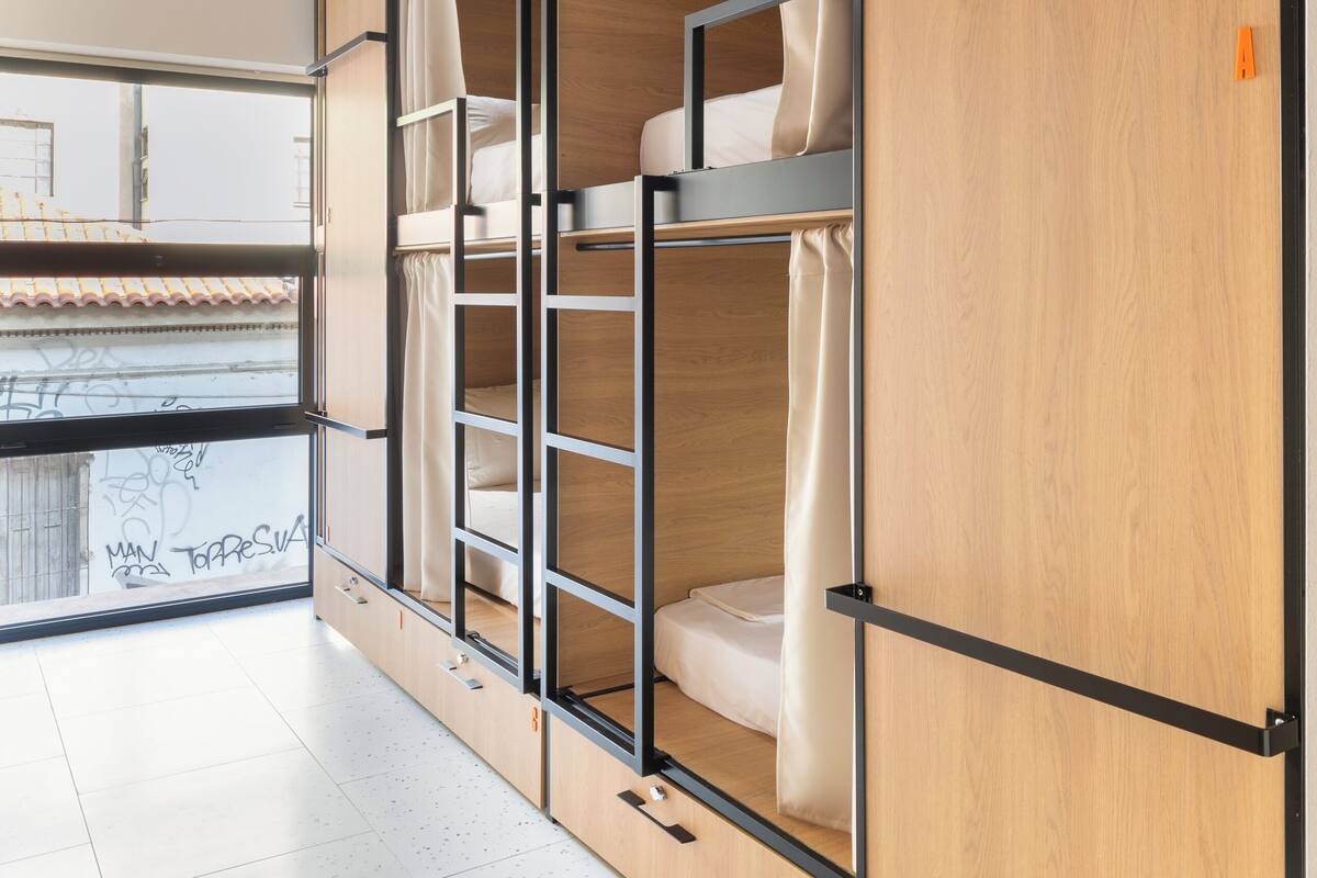A modern room with a bunk bed, wooden wardrobe, and a window with a view of the outside.