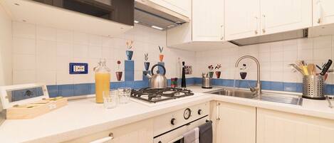 A kitchen with white cabinets, a gas stove, a microwave, and a sink.