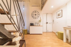 Una sala moderna con una escalera, un armario blanco, un reloj y un cuadro en la pared.