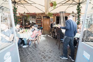 An outdoor café with tables and chairs, a man serving food, and a sign for 'Cucina Romana'. - Campo de’ Fiori 35 - modern and quiet, in the center of Rome (Roma)