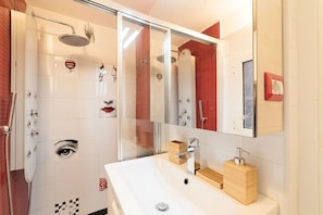 A modern bathroom with a glass shower enclosure, a white sink with a wooden soap holder, and a mirror above the sink. - Campo de’ Fiori 35 - modern and quiet, in the center of Rome (Roma)