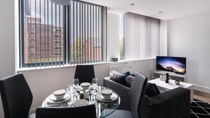 Un salon moderne comprenant un coin repas, de grandes fenêtres, un téléviseur à écran plat et un espace salon confortable.