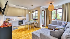 A modern kitchen with a dining area, a sofa, and a large window with curtains.