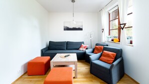 A modern living room with a grey sectional sofa, orange ottomans, and a wooden coffee table.