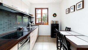 A modern kitchen with a stove, sink, and window. - Apartamenty Sun & Snow Okrzei (Karpacz)