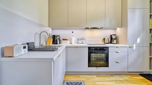 A modern kitchen with a dishwasher, oven, and coffee maker.