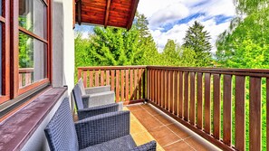 A balcony with wicker furniture and a wooden railing, overlooking a lush green landscape. - Apartamenty Sun & Snow Okrzei (Karpacz)