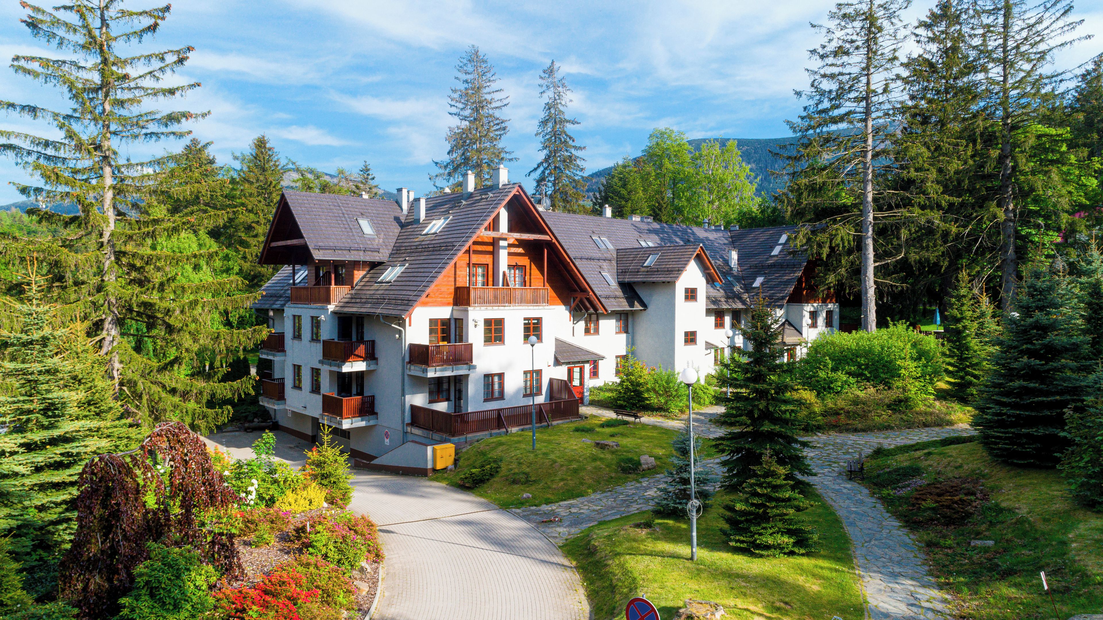 Un chalet à plusieurs étages, doté d’un toit en pente, de balcons en bois et d’un chemin de pierre menant à l’entrée.
