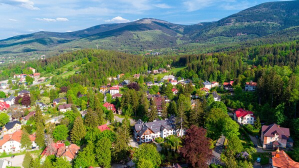 A residential area with houses surrounded by dense forests and hills in the background. - Apartamenty Sun & Snow Okrzei (Karpacz)