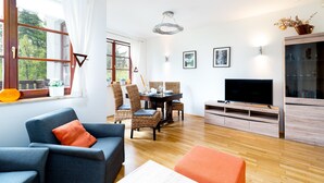 A modern living room with a sofa, dining table, chairs, a TV, and a cabinet.