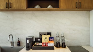 A kitchen with a marble countertop, a coffee machine, a tea kettle, a bottle of water, and a box of truffle salt. - Ayona Villa Canggu by Ini Vie Hospitality (Canggu)