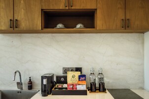 A kitchen with a marble countertop, a coffee machine, a tea kettle, a bottle of water, and a box of truffle salt.