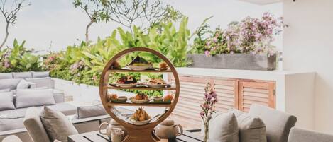 Una mesa de comedor con un frutero escalonado y un florero con flores.