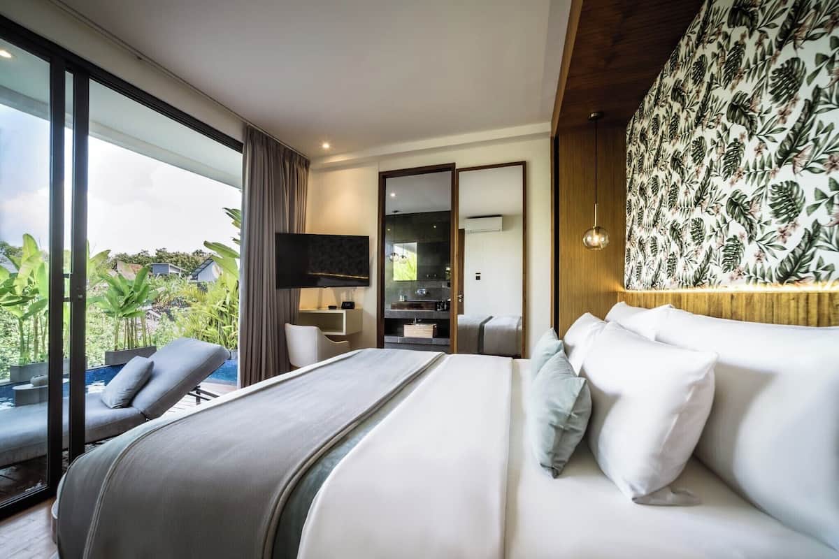 A modern hotel room with a large bed, a TV, a desk, and a balcony with a pool.