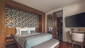 A modern bedroom with a large bed, a TV, a bedside table, and a mirror. - Ayona Villa Canggu by Ini Vie Hospitality (Canggu)