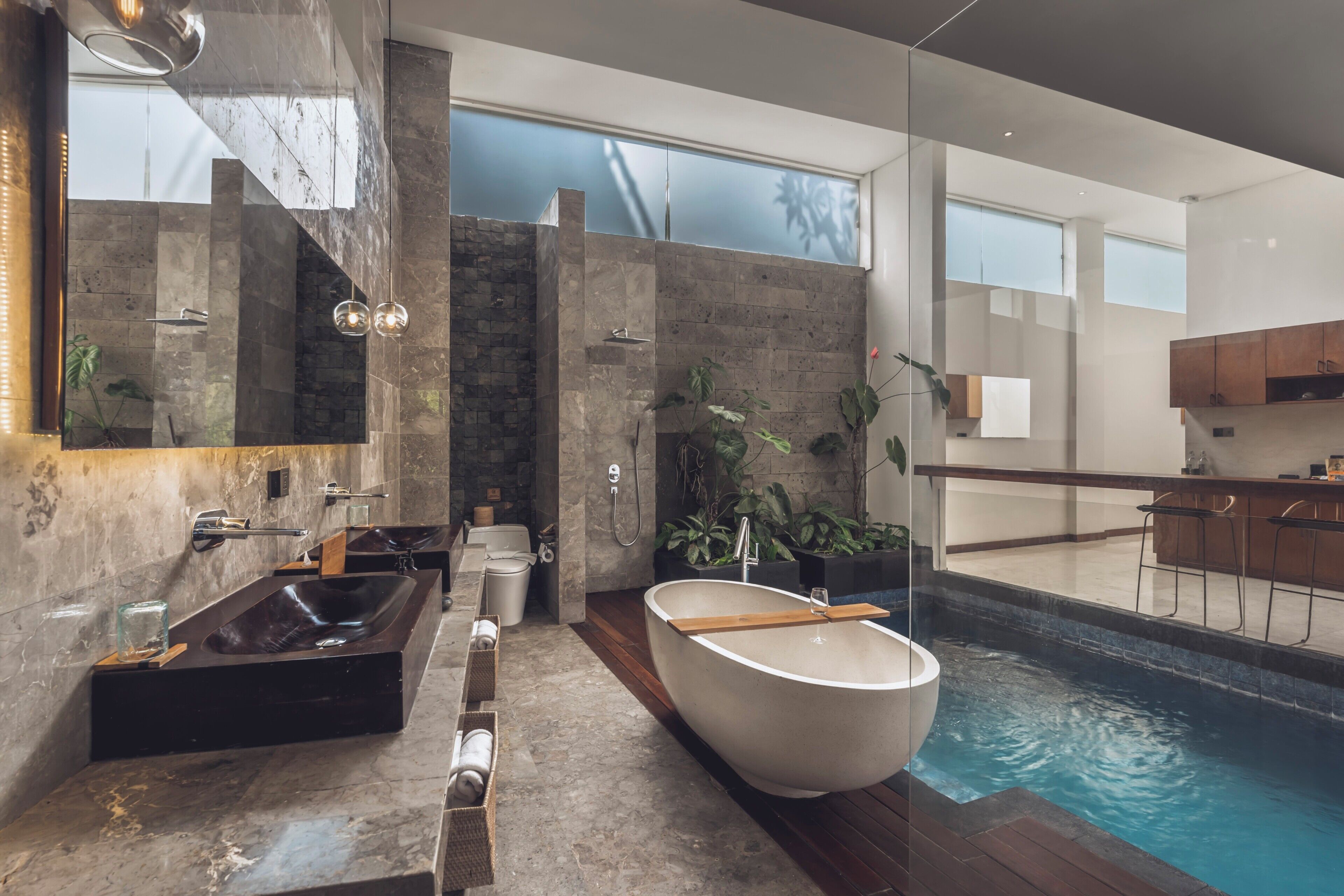 A modern bathroom with a large bathtub, a shower, and a glass-enclosed pool.