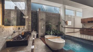 A modern bathroom with a large bathtub, a shower, and a glass-enclosed pool.