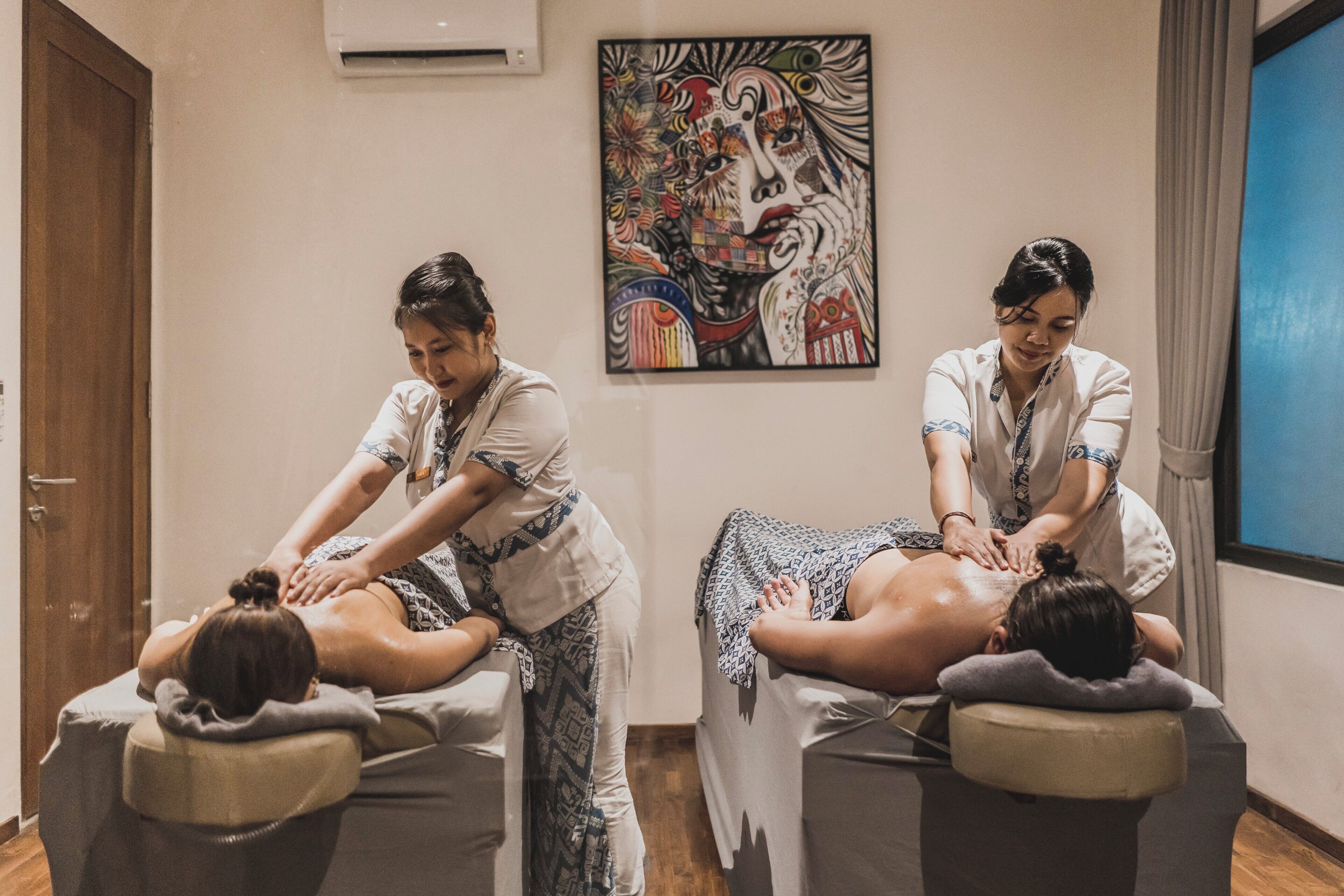 Un cuarto de terapia de masajes con dos clientes recibiendo masajes.