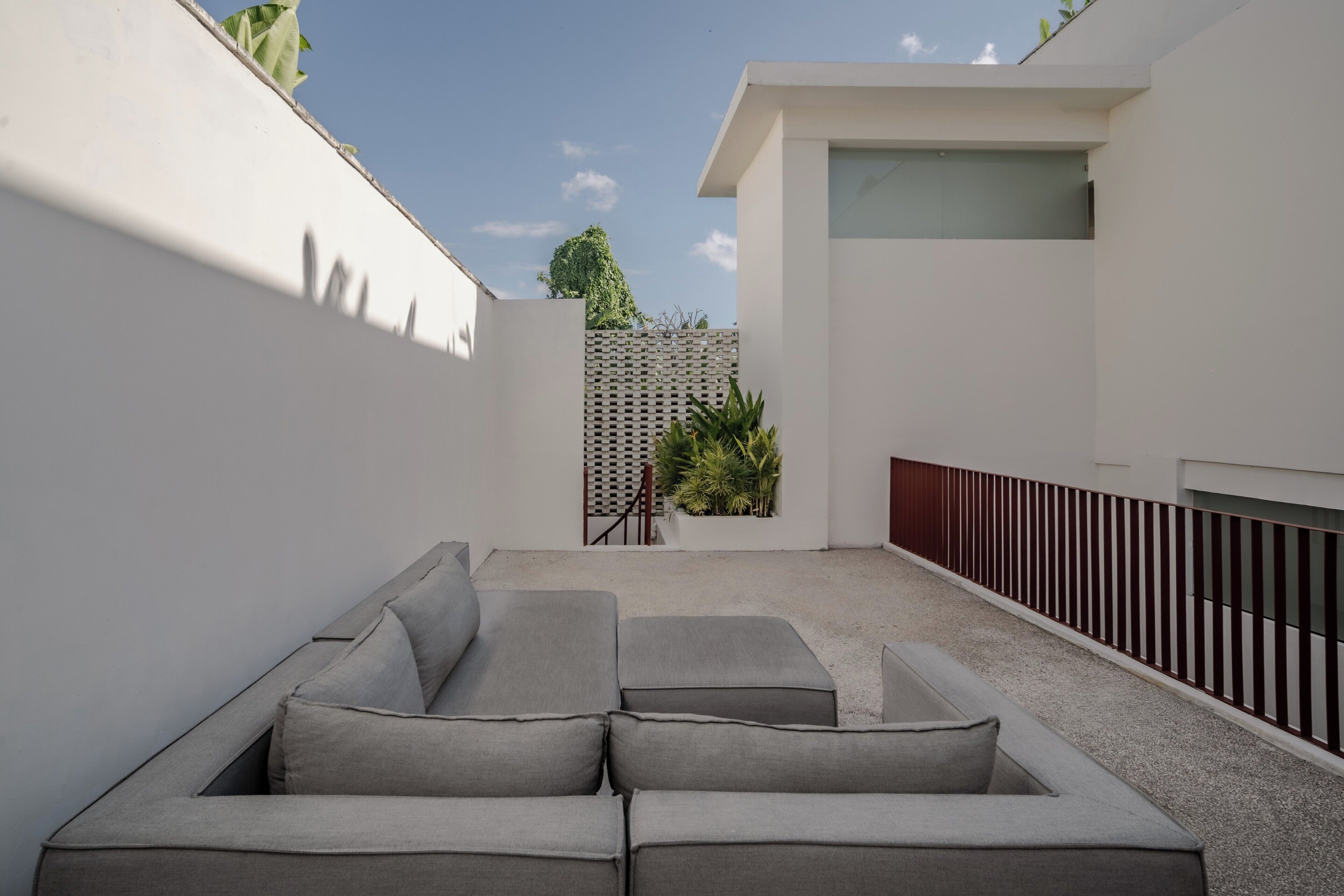 Un espace extérieur moderne aménagé avec des sièges, un mur blanc et une clôture en bois.