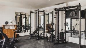 A gym with weightlifting equipment, exercise bikes, and a mirror reflecting the space. - Ayona Villa Canggu by Ini Vie Hospitality (Canggu)