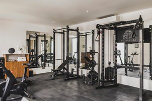 A gym with weightlifting equipment, exercise bikes, and a mirror reflecting the space.