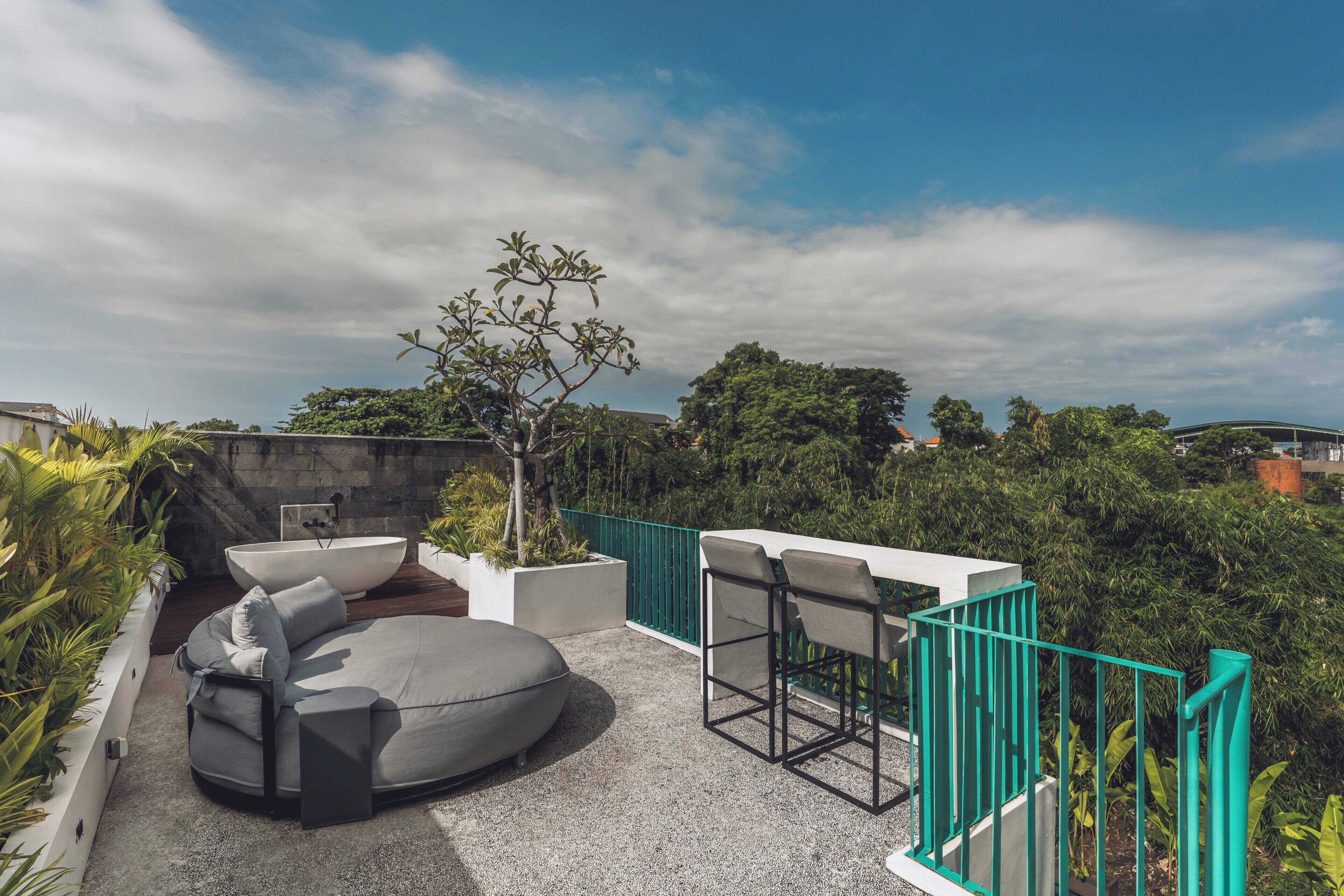 A rooftop terrace with a seating area, a tree, and a view of the surrounding landscape.