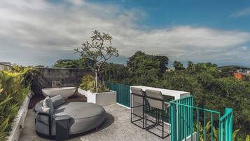 A rooftop terrace with a seating area, a tree, and a view of the surrounding landscape.