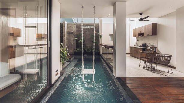 A modern interior with a central water feature, a kitchen area, and a dining space. - Ayona Villa Canggu by Ini Vie Hospitality (Canggu)