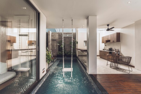 A modern interior with a central water feature, a kitchen area, and a dining space. - Ayona Villa Canggu by Ini Vie Hospitality (Canggu)