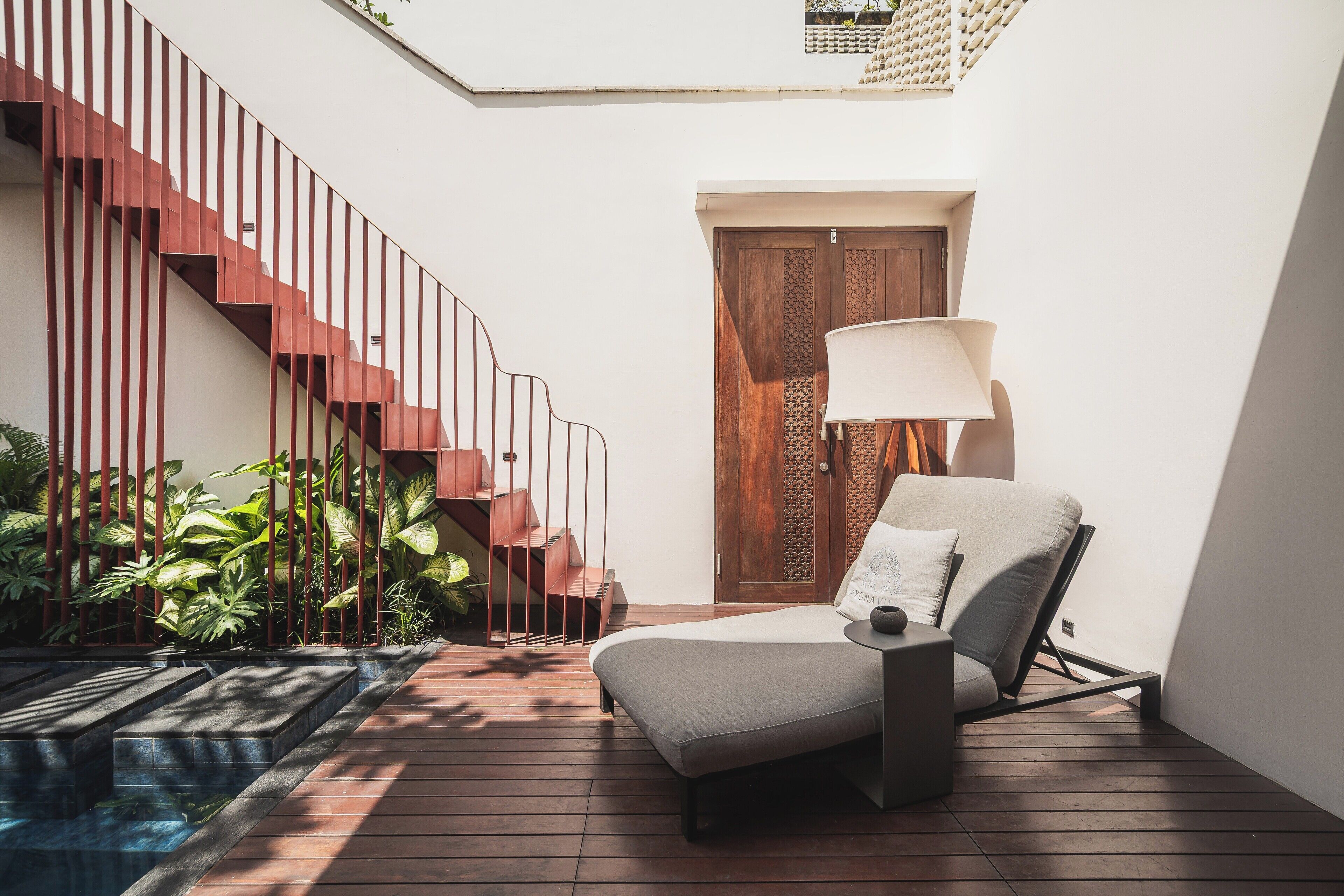 A modern interior with a wooden staircase, a lounge chair, and a door with decorative panels.