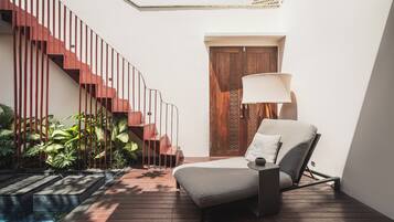 A modern interior with a wooden staircase, a lounge chair, and a door with decorative panels.